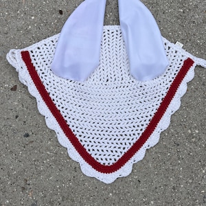 May include: White crochet horse fly bonnet with red trim and white satin ear covers.