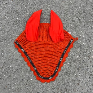 May include: Orange horse fly bonnet with black trim and ear covers. The trim has the text "HERMES PARIS" repeated around the edge.