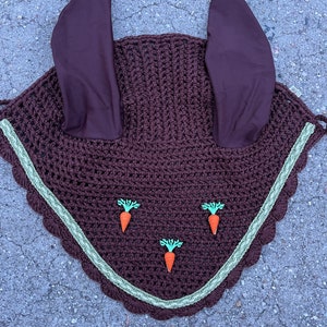 May include: A brown horse fly bonnet with green and orange carrot decorations and brown ear covers.