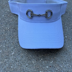 May include: White visor with a silver and rhinestone equestrian bit design.