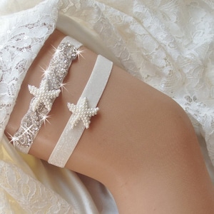 May include: White bridal garter with a sparkly rhinestone and pearl starfish design. The garter is made of white satin and lace.
