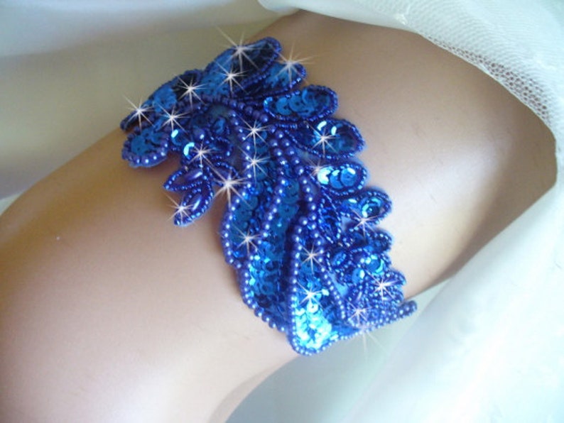 Puede incluir: Una liga azul con lentejuelas con un dise&ntilde;o de hoja. Las lentejuelas son iridiscentes y brillan a la luz.