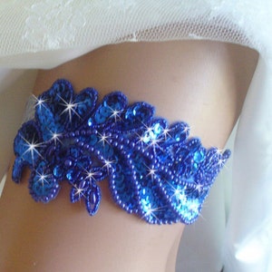 Puede incluir: Una liga de novia azul real con un dise&ntilde;o floral y lentejuelas brillantes.