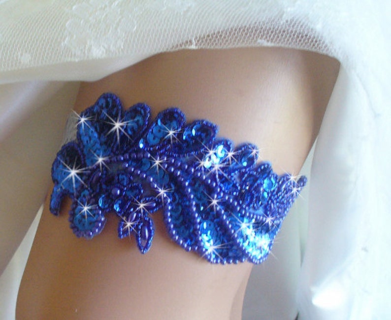 Puede incluir: Una liga de novia azul real con un dise&ntilde;o floral y lentejuelas brillantes.