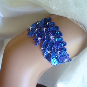 Puede incluir: Una liga azul con un dise&ntilde;o de lentejuelas. La liga est&aacute; decorada con peque&ntilde;as lentejuelas y cuentas azules.