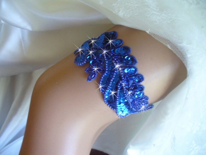 Puede incluir: Una liga azul con un dise&ntilde;o de lentejuelas. La liga est&aacute; decorada con peque&ntilde;as lentejuelas y cuentas azules.