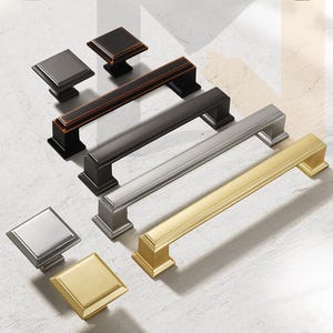 Può includere: Cinque maniglie per armadi in diverse finiture, tra cui oro, argento e bronzo. Le maniglie sono tutte rettangolari con un bordo smussato e un pomo quadrato all'estremità.