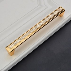 May include: Gold cabinet door pull with a row of clear crystals embedded in the surface.