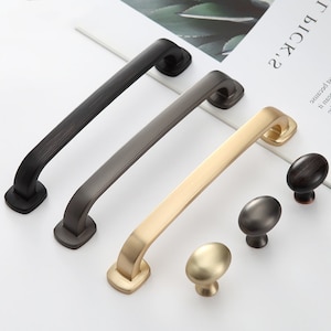 May include: Three cabinet pulls in black, dark gray, and gold metal finishes. Three matching knobs in the same finishes.