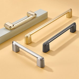 以下が含まれることがあります： 金、銀、黒の3種類の仕上げのキャビネットプル。各プルは、丸みを帯びたエッジを持つシンプルでモダンなデザインです。