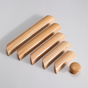 May include: Set of six wooden cabinet knobs in various sizes, with a rounded rectangular shape. The knobs are made of light brown wood and have a smooth finish. A small round knob is also included.