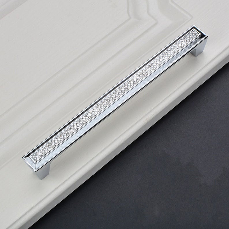 May include: A silver cabinet door handle with a row of clear rhinestones.