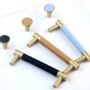May include: Four cabinet knobs and three cabinet pulls with leather coverings in blue, brown, and black. The hardware is made of brass and has a polished finish.