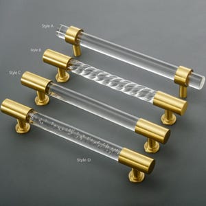 May include: Four styles of clear acrylic cabinet pulls with gold metal end caps. The pulls are labeled "Style A", "Style B", "Style C", and "Style D".