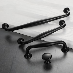 May include: Four black metal cabinet pulls in different sizes. The pulls have a simple, curved design.
