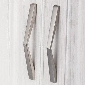 May include: Two silver cabinet door pulls with a geometric, angled design.