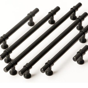 Könnte beinhalten: Satz schwarzer Metall-Schrankgriffe mit zylindrischem Design. Die Griffe sind in verschiedenen Größen.