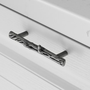 Op de afbeelding: Een zilverkleurige ladegreep in de vorm van een tak met een getextureerd oppervlak.