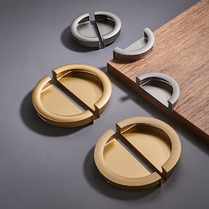 May include: Two sets of gold and silver half-circle cabinet door pulls. The pulls are made of metal and have a smooth, polished finish. The gold pulls have a textured surface.