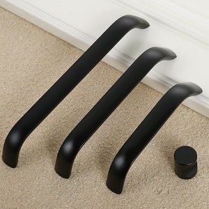 May include: Three black cabinet pulls with a rounded rectangular shape and a single knob pull.