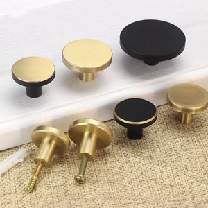 May include: Assortment of round cabinet knobs in gold and black finishes. Some knobs have a smooth surface, while others have a textured surface.