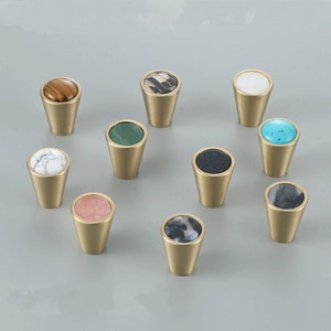 Puede incluir: Surtido de diez pomos de armario de latón con incrustaciones de piedra de diferentes colores. Los pomos son de forma cónica con la parte superior redonda.