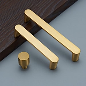 May include: Two gold-toned cabinet pulls with rounded edges and a smaller gold-toned knob.