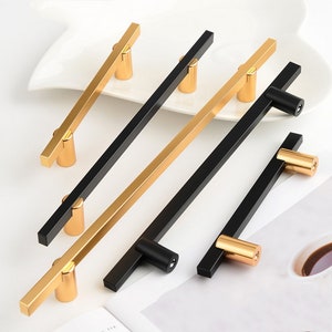 May include: Four cabinet pulls with a black and gold finish. The pulls are rectangular with rounded edges and have a gold accent on the end.