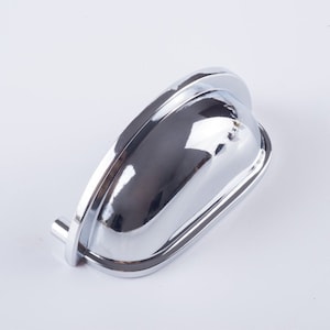 May include: A chrome cabinet pull with a curved, oval shape. The pull has a smooth, shiny finish.