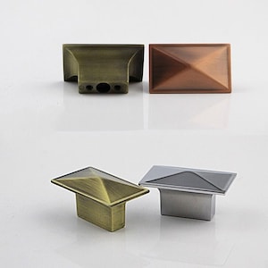 Puede incluir: Cuatro pomos de armario con una parte superior en forma de pir&aacute;mide. Los pomos est&aacute;n en tres acabados diferentes: lat&oacute;n antiguo, cobre y plata.