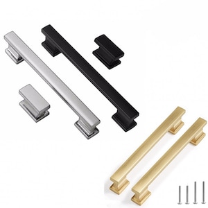 May include: Three sets of cabinet pulls in black, silver, and gold. Each set includes two long pulls and two small square pulls. The pulls are made of metal and have a modern design.