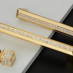 May include: Two gold cabinet pulls with a row of clear rhinestones and a smaller gold knob with clear rhinestones.