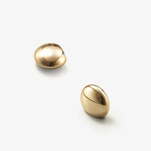 May include: Two gold-coloured, smooth, rounded, decorative door knobs.