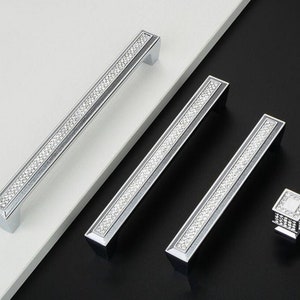 May include: Three silver cabinet pulls with a diamond-like pattern and a single silver knob with a diamond-like pattern.