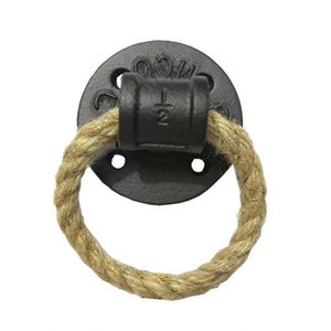 May include: A black cast iron door pull with a rope handle. The pull has a round base with six holes and the text "1/2" on the handle.