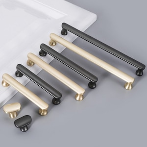 May include: A set of eight cabinet pulls in two finishes: gold and black. The pulls are all the same size and shape, with a rounded rectangular design.