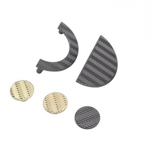 May include: A set of five cabinet knobs and pulls in two finishes: black and gold. The knobs and pulls feature a geometric, woven pattern.