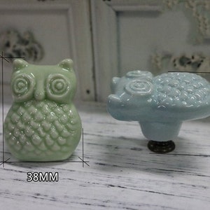 May include: Two ceramic drawer pulls, one shaped like an owl and one shaped like a cloud. The owl is green and the cloud is light blue. Both are 38 mm wide and the owl is 48 mm tall.