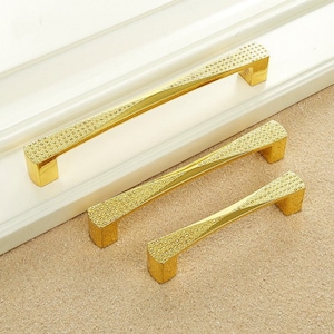 May include: Three gold-toned cabinet door pulls with a textured, diamond-like pattern. The pulls are arranged in descending size order.