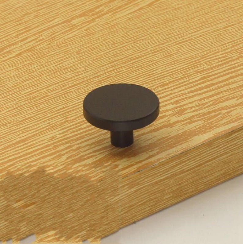 May include: Black round cabinet knob with a flat top and a cylindrical base.