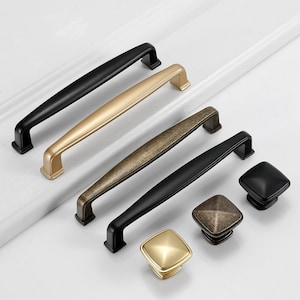 Puede incluir: Cuatro tiradores de armario en acabados negro, dorado y latón antiguo. Los tiradores son rectangulares con bordes redondeados. También hay tres pomos cuadrados a juego en negro, dorado y latón antiguo.