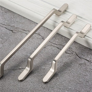 May include: Three silver cabinet pulls with a curved design. The pulls are different sizes.
