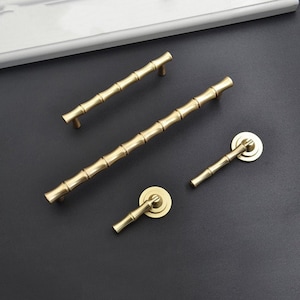 May include: Four brass cabinet pulls in a bamboo design. Two are long pulls and two are smaller knobs.