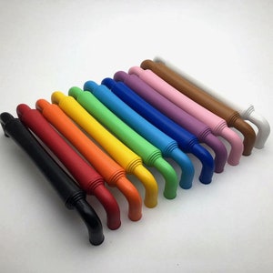 May include: A set of 14 colourful cabinet door pulls with a ribbed design. The pulls are arranged in a rainbow pattern, starting with black and ending with white.