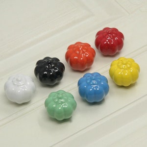 以下が含まれることがあります： さまざまな色（白、黒、オレンジ、赤、黄、水色、緑）のセラミック製かぼちゃ型の引き出しノブが7個あります。