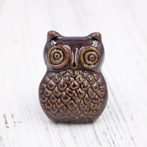 May include: A brown ceramic owl figurine with a textured surface and detailed eyes. The owl is a popular decorative item for homes and gardens.