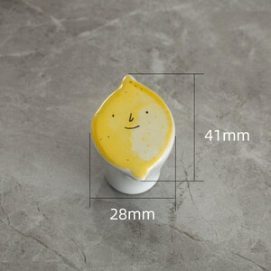 May include: A whimsical ceramic lemon-shaped knob with a smiling face. The yellow top is 1.6 inches long and 1.1 inches wide, with a white base. This decorative knob is suitable for cabinets and drawers.