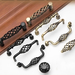May include: A set of eight decorative cabinet knobs and pulls in black and antique brass finishes. The knobs and pulls feature a twisted wire design.