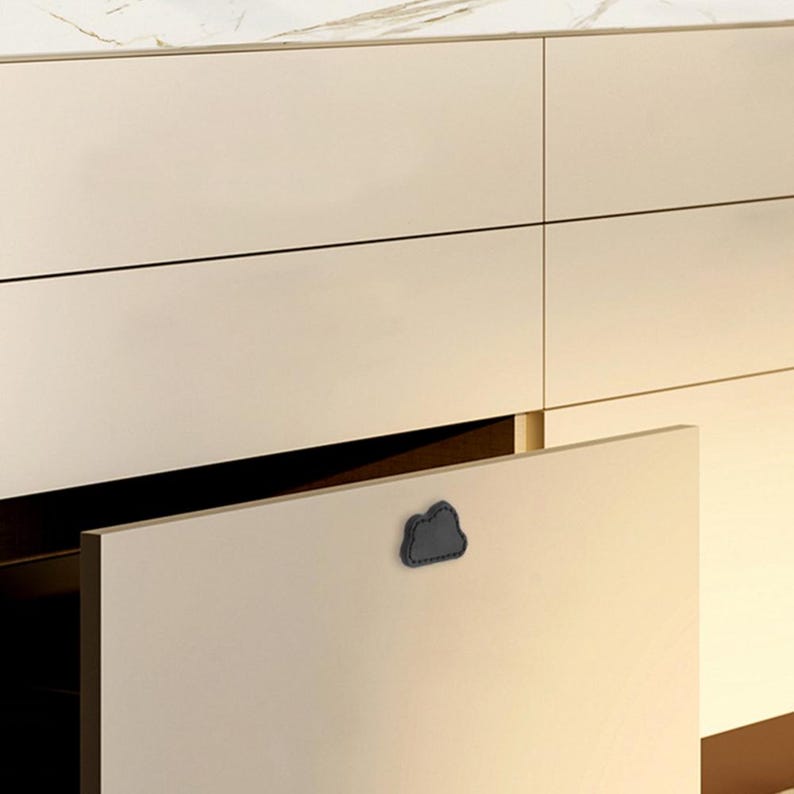 May include: A white cabinet with a drawer that is open. The drawer has a black cloud-shaped pull.
