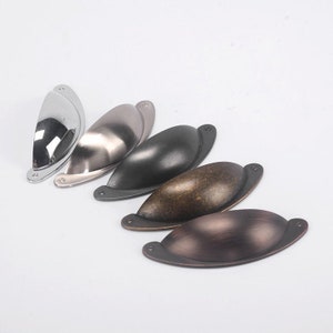 Puede incluir: Cinco tiradores de armario en diferentes acabados: cromo pulido, níquel cepillado, negro, latón antiguo y bronce aceitado. Los tiradores tienen todos la misma forma, un rectángulo curvo ligeramente redondeado.